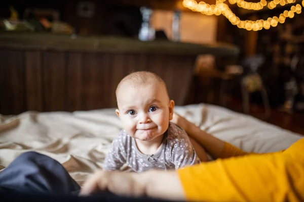 Bebê adorável e feliz deitado no estômago acima de uma cama — Fotografia de Stock