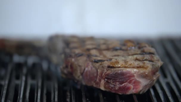 흰 배경이 있는 그릴 위에 놓인 얼음처럼 보이는 고기 조각 — 비디오