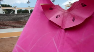 Pembe boğa güreşçisi pelerini yavaşça sallanıyor.