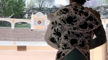 Beyaz ve siyah pelerinli boğa güreşçisi yavaşça ringe giriyor.