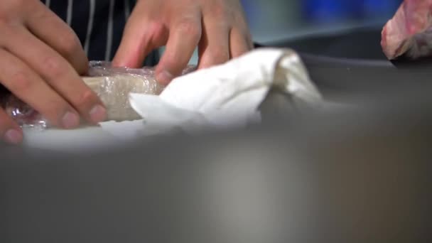 Mãos masculinas cuidadosamente desembrulhando um pedaço de carne com aparência suculenta — Vídeo de Stock
