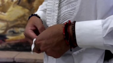 Erkek boğa güreşçisi elleri sakince beyaz gömleğini bağlıyor.