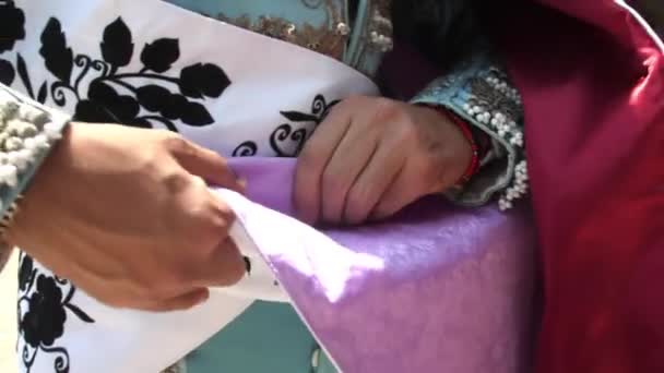 Male bullfighter hands folding a purple and red cape — Stock Video