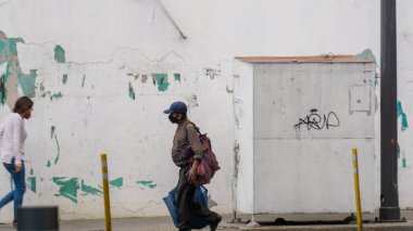 Meksika 'dan gelen bir sokakta yürüyen maskeli insanlar.