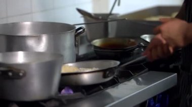 Lokanta mutfağında ocakta yemek pişiren erkek eller.