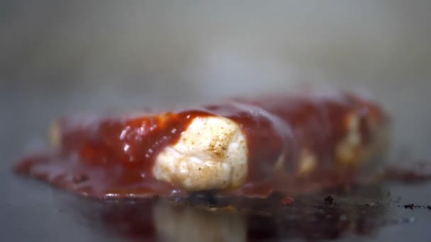 Pouring red sauce on juicy-looking steak above a griddle — Stock Video