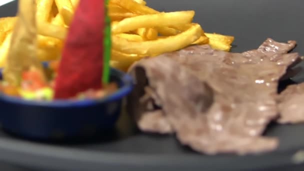 Barevné plátky tortilly, hranolky a tenký steak na černém talíři — Stock video