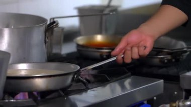 Lokanta mutfağında ocakta yemek pişiren erkek eller.