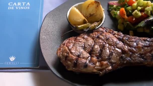 Restaurant-Menü auf einem Tisch neben gegrilltem Fleisch — Stockvideo