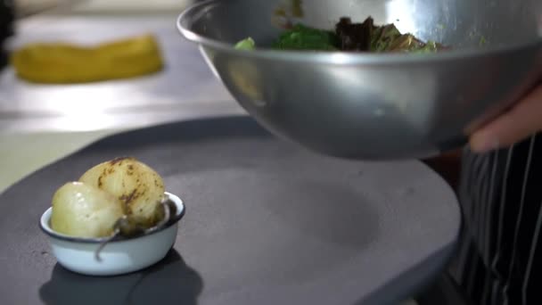 Pinces ajoutant des tranches de tomates rôties et de nopal à une assiette noire — Video