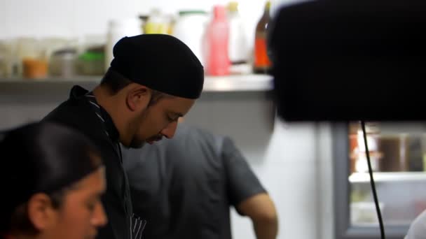 Chefs hispanos vestidos de negro cocinando en una cocina de restaurante — Vídeo de stock