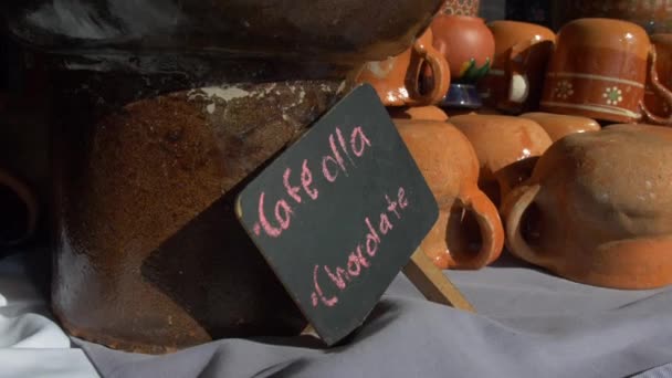 Garnki gliny i czarny znak z różowym hiszpańskim tekstem na stole — Wideo stockowe