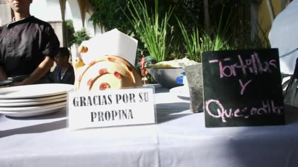 Černá značka s růžovým španělským textem na stole s vařit a rostliny jako pozadí — Stock video