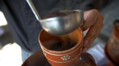 Erkek elleri, el yapımı kilden bir fincanda kahve servisi yapıyor.