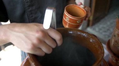 Erkek elleri, el yapımı kilden bir fincanda kahve servisi yapıyor.