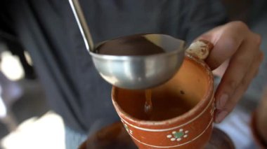 Erkek elleri, el yapımı kilden bir fincanda kahve servisi yapıyor.