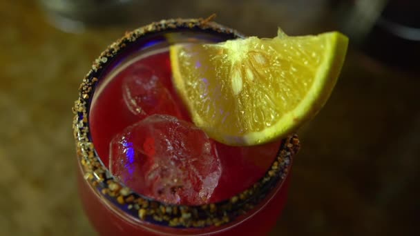 Красный алкогольный напиток в стеклянном кубке с апельсиновым ломтиком — стоковое видео