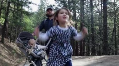 Mutlu küçük kız babasının ve küçük kız kardeşinin önünde zıplıyor.