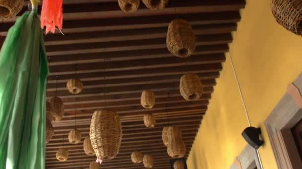 Pinatas y lámparas hechas a mano colgando del techo de madera en el restaurante — Vídeo de stock