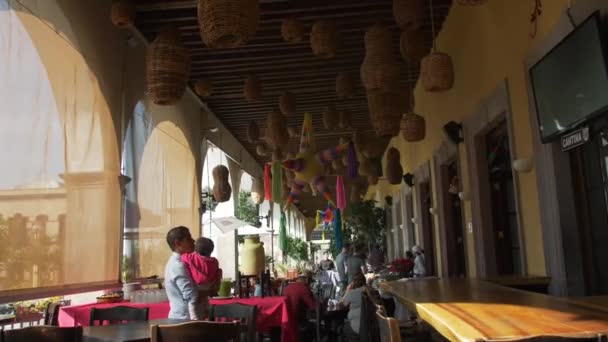 Personas sentadas en mesas en restaurante con piñatas colgando del techo — Vídeo de stock
