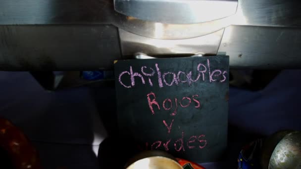 Чорний знак з рожевим іспанським текстом біля глиняного горщика нарізаного м'яса. — стокове відео