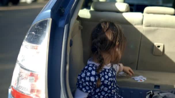 Gelukkig klein meisje spelen met leerkaarten in de rug van een voertuig — Stockvideo