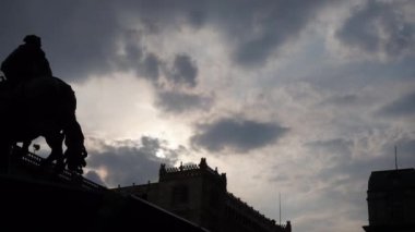 Arka planda bulutlu bir gökyüzü olan ata binen bir adamın silueti.