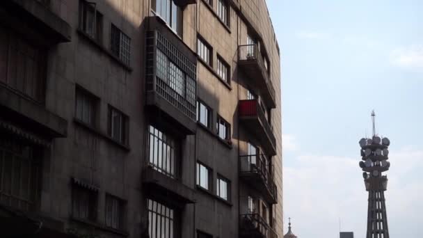 Shady apartment building with a telecommunications tower in the distance — Stock Video