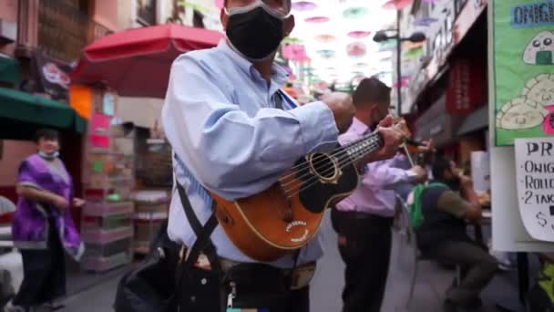 Två män bär ansiktsmasker spela instrument i Chinatown — Stockvideo