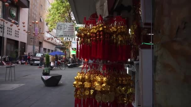 Goldene und rote chinesische Amulette zum Verkauf außerhalb eines Gebäudes — Stockvideo