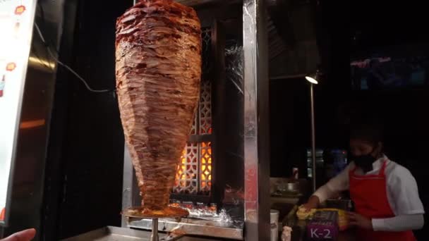 Mãos masculinas cortando um tronco pastor mexicano tradicional fora de um restaurante — Vídeo de Stock