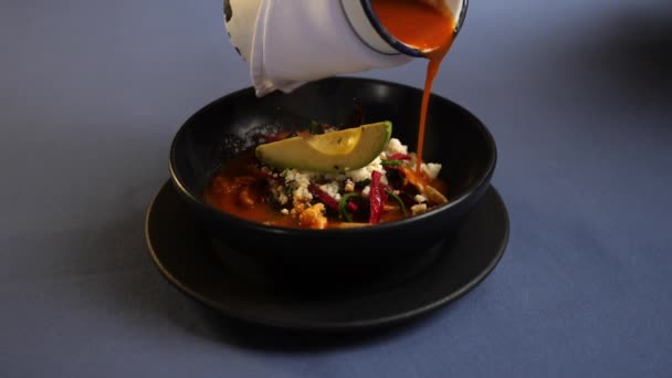 Verter salsa roja en una corteza de cerdo, rodajas de tortilla y un plato de aguacate — Vídeos de Stock