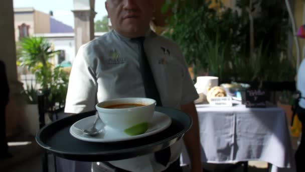 Латиноамериканский официант в мексиканском ресторане ходит и держит в руках белую миску — стоковое видео