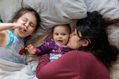 Anne ve iki küçük kızı yatağa uzanıyorlar.