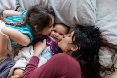 Anne ve iki küçük kızı yatağa uzanıyorlar.