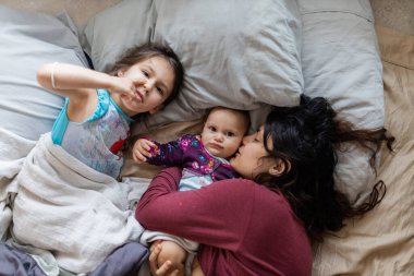 Anne ve iki küçük kızı yatağa uzanıyorlar.