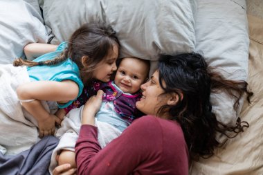 Anne ve iki küçük kızı yatağa uzanıyorlar.