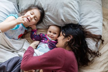 Anne ve iki küçük kızı yatağa uzanıyorlar.