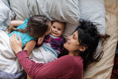 Anne ve iki küçük kızı yatağa uzanıyorlar.