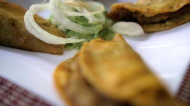 Meksika sepeti tacoları ve beyaz tabakta soğan dilimleri.