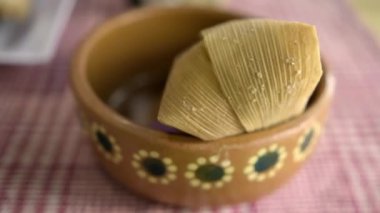 Beyaz ve kırmızı kareli masa örtüsünün üstünde kil kasede Tamale.