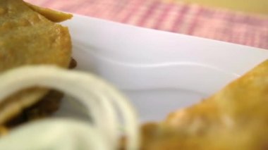 Meksika sepeti tacoları ve beyaz tabakta soğan dilimleri.