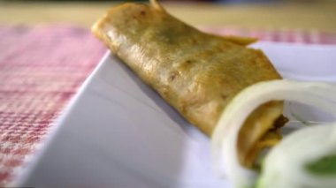 Meksika sepeti tacoları ve beyaz tabakta soğan dilimleri.