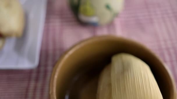 Tamale and vanilla atole in clay cups above a checkered tablecloth — Stock Video