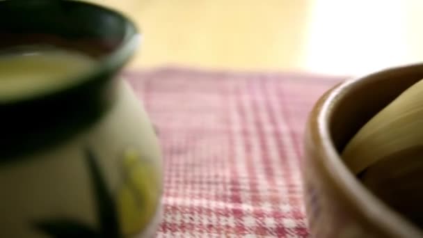 Tamales y atole de vainilla en tazas de arcilla sobre un mantel a cuadros — Vídeos de Stock