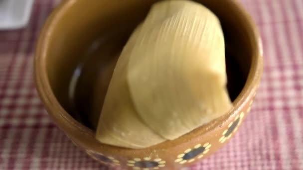 Tamale and vanilla atole in clay cups above a checkered tablecloth — Stock Video