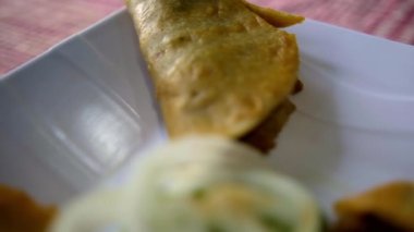 Meksika sepeti tacoları ve beyaz tabakta soğan dilimleri.