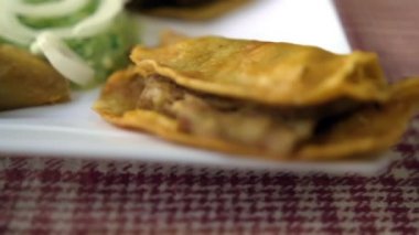 Meksika sepeti tacoları ve beyaz tabakta soğan dilimleri.