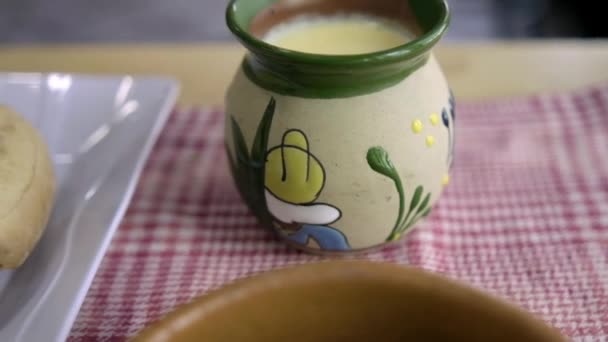 Tamal y atole de vainilla en tazas de arcilla sobre un mantel a cuadros — Vídeos de Stock