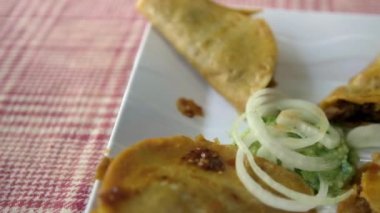 Meksika sepeti tacoları ve beyaz tabakta soğan dilimleri.